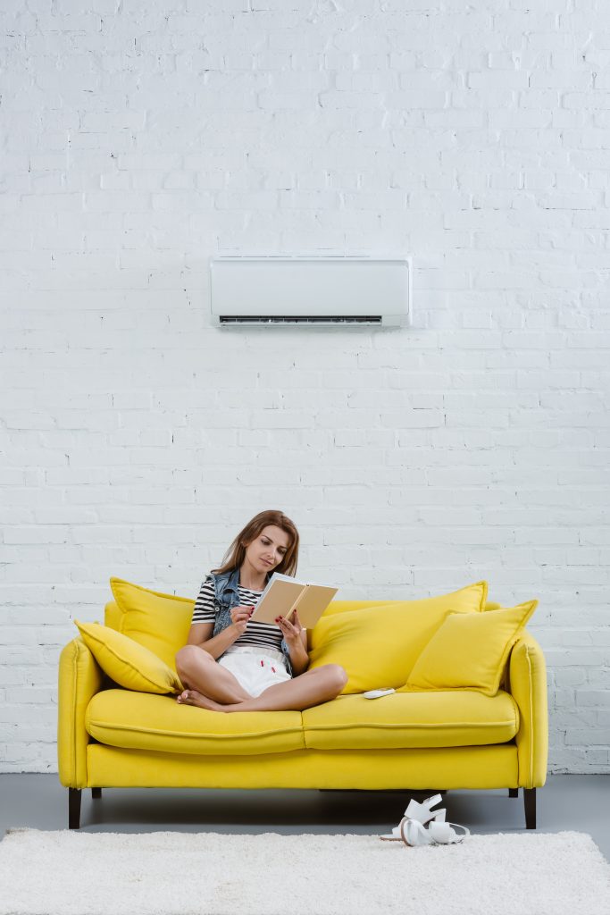 beautiful young woman reading book on sofa under a 2023 11 27 05 04 19 utc Aire Acondicionado Nerja